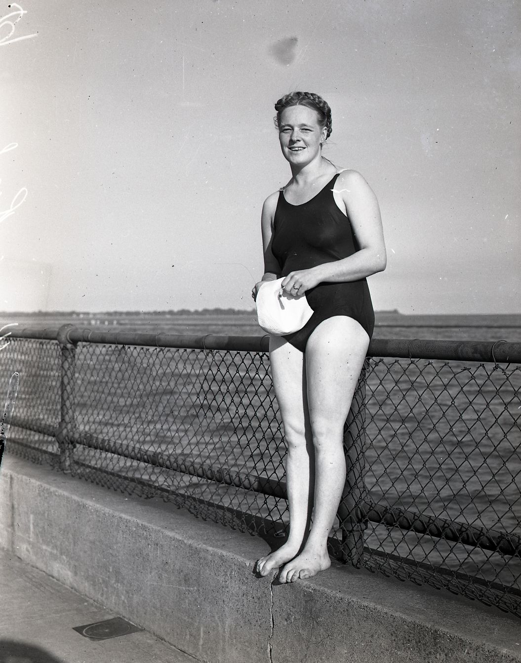 Winnie Roach-Leuszler stands against a guard rail in her swimsuit.